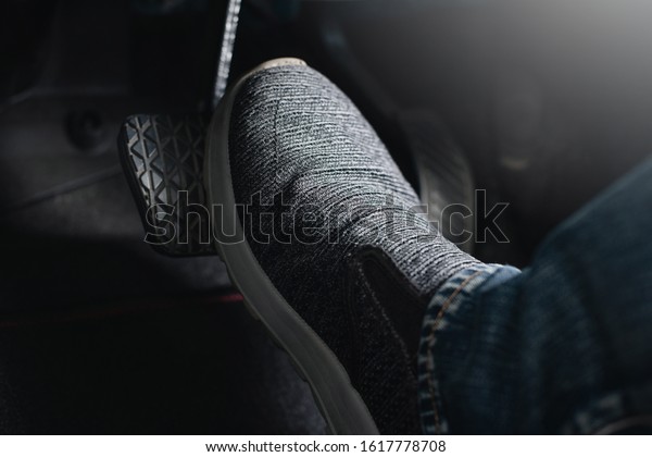 Close up the foot pressing brake pedal of a car.\
Driver stopping the car.