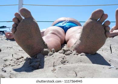 Close Up The Foot Of The Sunbathing Fat Man Photographed In A Comical Foreshortening