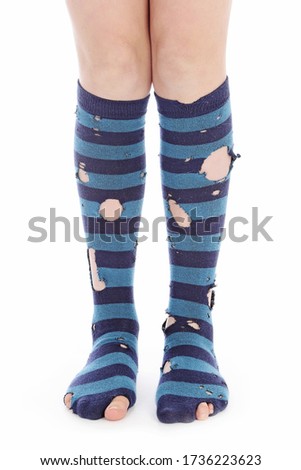 
close up foot young girl wearing tall blue striped socks with holes on white isolated studio background