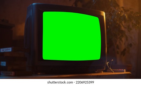 Close Up Footage Of A Dated TV Set With Green Screen Mock Up Chroma Key Template Display. Nostalgic Retro Nineties Technology Concept. Vintage Television Display In Living Room.