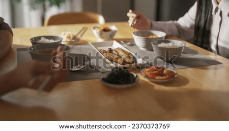 Close Up Footage Focusing on Tasty Dishes on a Dining Table with Rice Bowls, Spicy Asian Soup, Fish and Vegetables. Young Asian Man and Woman Having a Korean Lunch at Home in the Kitchen