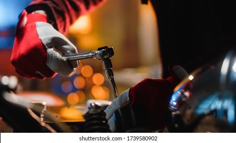 Close Up Footage of a Mechanic Bike Enthusiast in Red Work Gloves in a Garage or a Creative Workshop. Talented Person Working on a Custom Bike with a Ratchet. - Powered by Shutterstock