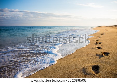 close up of footprints in the sand on the beach at sunset