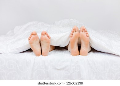 Close Up Of Four Feet In A Bed