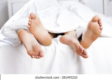 Close up of four feet in a bed