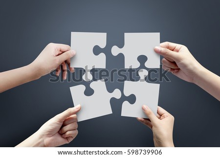 Close up of four hands holding jigsaw, Concept for teamwork Building a success.