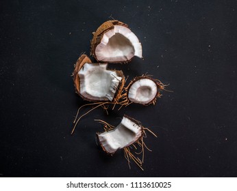close up four isolated pieces of broken coconut on dark chalkboard 