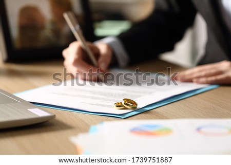 Close up of freelance woman hands signs divorce papers sitting on a desk at homeoffice at night