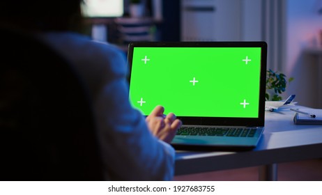 Close up of freelancer typing on laptop with green screen sitting at desk in start up office overworking. Manager watching desktop monitor display with green mockup, chroma key, during night time - Powered by Shutterstock