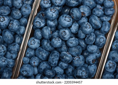 Close up fresh blueberry berries in plastic containers in brown cardboard box on retail display, elevated top view, directly above - Shutterstock ID 2205594457