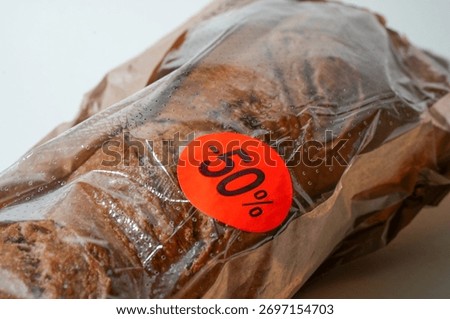 Close up of fresh bread featuring a 50% discount sticker, symbolizing reduced food prices and supermarket markdowns