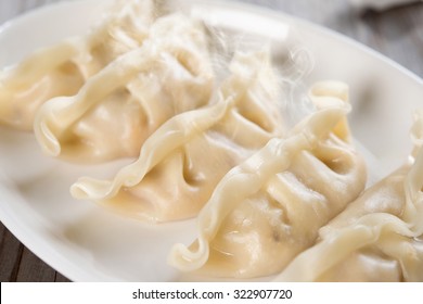 Close Up Fresh Dumpling On Plate With Hot Steams. Chinese Food On Old Wooden Background. 