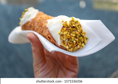 Close up of a fresh Italian Cannoli, held by hand