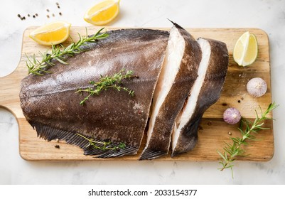 Close Up Of Fresh Raw Halibut Fish On Wodden Board With Herbs And Lemon. Top View. Omega 3 Fats Good For Mental Clarity. Brain Food