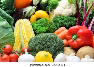 Close up of fresh raw organic vegetable produce, assortment of corn, peppers, broccoli, mushrooms, beets, cabbage, parsley, tomatoes, isolated on light background - Powered by Shutterstock