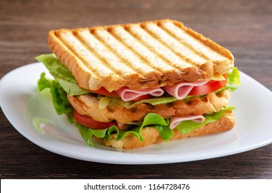 Close Up Of Fresh Sandwich With Ham, Bacon,tomatoes On White Plate