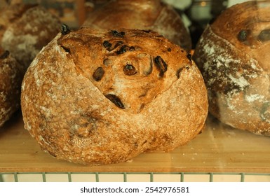 Close up of freshly baked sourdough bread displayed on a wooden shelf in a glass showcase in cafe bakery. Healthy artisan bread with hard crispy crust. - Powered by Shutterstock