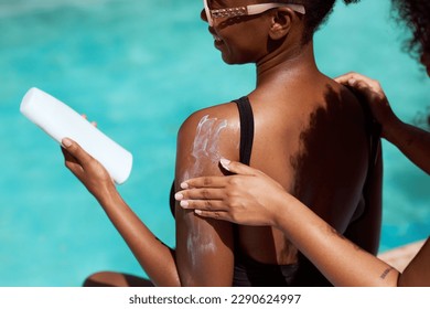 Close up of friend applying sunscreen, two Black women protecting skin in sun - Powered by Shutterstock