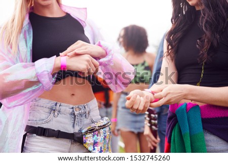 Close Up Of Friends At Entrance To Music Festival Putting On Security Wristbands