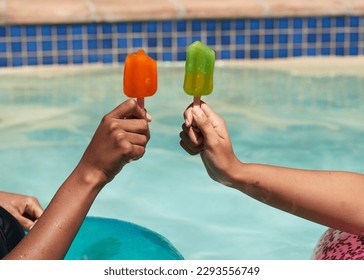 Close up of friends holding ice lolly popsicles in the swimming pool, beat heat