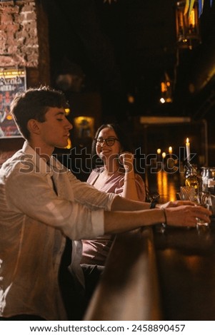 Close friends relax after hard week at work and drink alcoholic beverages at bar. Upset guy speak with lady in pink dress in club