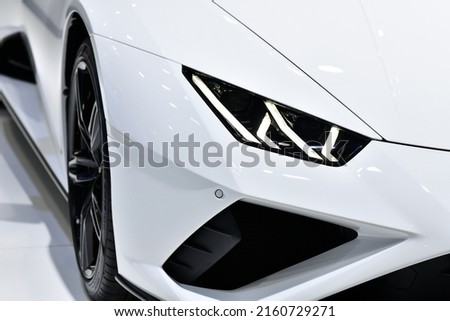 Close up front headlights of white super car on black background, copy space	