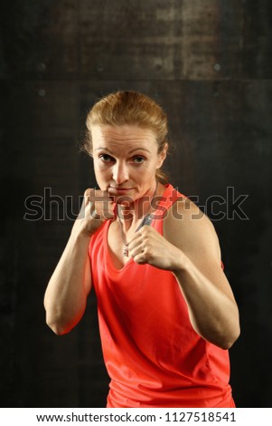 Similar – Close up front portrait of one young mid adult athletic woman in sportswear in gym over dark background, standing in boxing stance with hands and fists, looking at camera