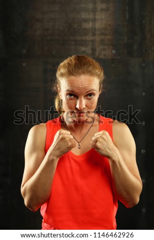 Similar – Close up front portrait of one young mid adult athletic woman in sportswear in gym over dark background, standing in boxing stance with hands and fists, looking at camera