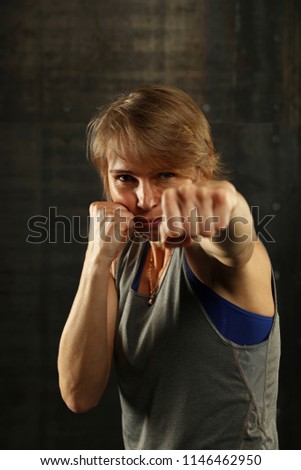 Image, Stock Photo Close up front portrait of one young middle age athletic woman in sportswear in gym over dark background, standing in boxing stance with hands and fists, looking at camera