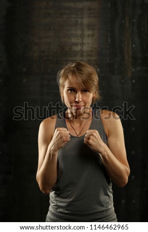 Similar – Close up front upper body portrait of one young athletic woman in sportswear in gym over dark background, looking at camera