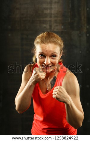 Similar – Close up front portrait of one young mid adult athletic woman in sportswear in gym over dark background, standing in boxing stance with hands and fists, looking at camera