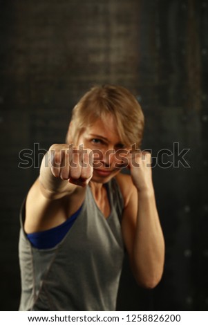 Similar – Image, Stock Photo Close up front portrait of one young middle age athletic woman in sportswear in gym over dark background, standing in boxing stance with hands and fists, looking at camera