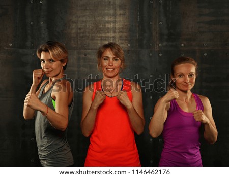 Similar – Close up front portrait of three young and middle age athletic women in sportswear in gym over dark background, looking at camera