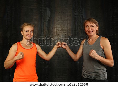 Similar – Close up front portrait of three young and middle age athletic women in sportswear in gym over dark background, looking at camera