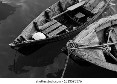 Close Up Of Front Side Of Small Fisherman Wooden Boat Moored In Port. Small Row Boat Floating , View From Top Angle Black And White Photography