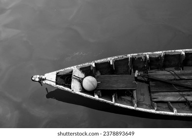 Close up of front side of small fisherman wooden boat moored in port. small row boat floating , view from top angle black and white photography