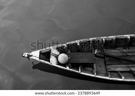 Close up of front side of small fisherman wooden boat moored in port. small row boat floating , view from top angle black and white photography