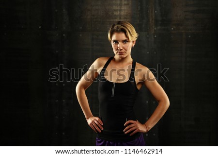 Similar – Close up front portrait of one young athletic woman in sportswear in gym over dark background, standing in boxing stance with hands and fists, looking at camera