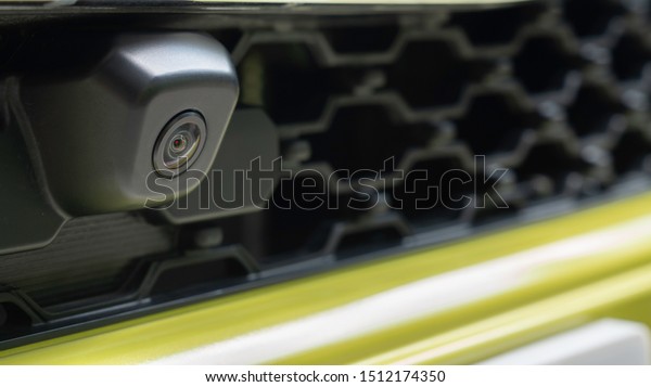 Close up of front view camera on a front\
grille mesh of the car. Parking assist systems. Automotive\
technologies concept. Selective focus. Copy\
space.