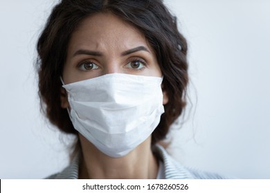 Close Up Front View Concerned Woman Face Portrait Wear Facial Mask Pose On Blue Studio Background Look At Camera Feels Afraid. COVID-19 Sars-cov-2 Epidemic Pandemic Virus Outbreak Protection Concept