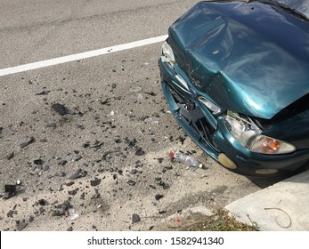 Close Up Front View Of A Dented Car After An Accident With Debris On The Asphalt Road