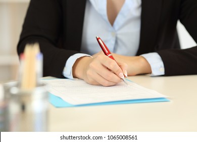 Close up front view of an office worker hands filling form on a desktop