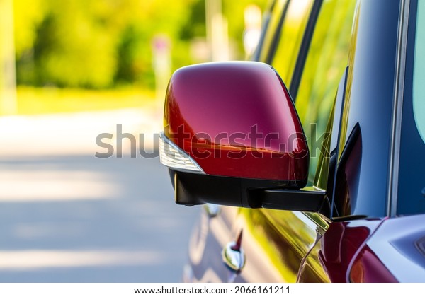 Close up front view of\
red car side mirror. Front rear view mirror on the car window. Car\
exterior details.
