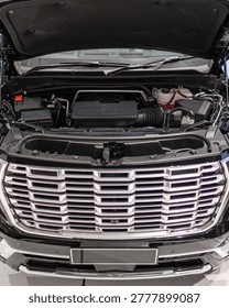 Close up front view showing engine bay and chrome grille with mechanical components and reflective surfaces under hood