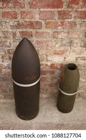 Close up front view of two ancient shells used during the world war I. Metallic explosive objects exposed in front of a red bricks wall. Vintage design. Abstract symbolic view of danger. 