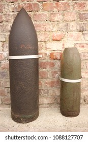 Close up front view of two ancient shells used during the world war I. Metallic explosive objects exposed in front of a red bricks wall. Vintage design. Abstract symbolic view of danger. 