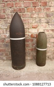 Close up front view of two ancient shells used during the world war I. Metallic explosive objects exposed in front of a red bricks wall. Vintage design. Abstract symbolic view of danger. 