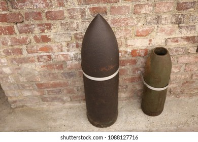 Close up front view of two ancient shells used during the world war I. Metallic explosive objects exposed in front of a red bricks wall. Vintage design. Abstract symbolic view of danger. 
