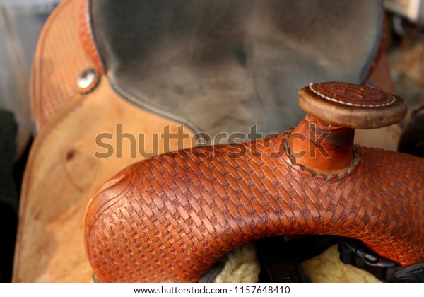 A close up of the front of a western saddle. Basket\
weave on a saddle horn.