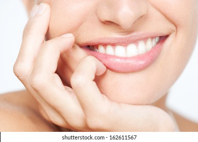 Nahaufnahme des frontalen Beauty-Sektion Porträt Blick auf eine junge Frau natürlichen Lächeln mit üppigen rosa Lippen auf ihrer Hand Lächeln mit weißen Zähnen, klassische Schönheit Details drinnen.